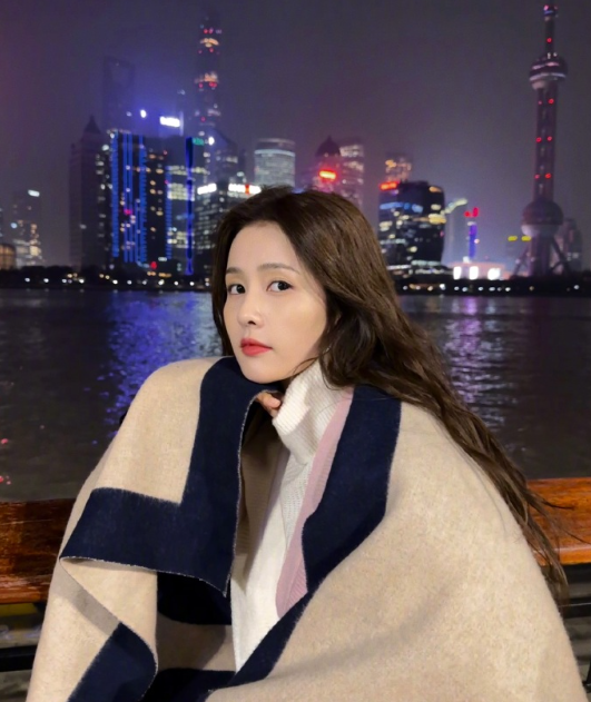 白鹿晒江边美照 披毛毯倚靠围栏侧颜精致 